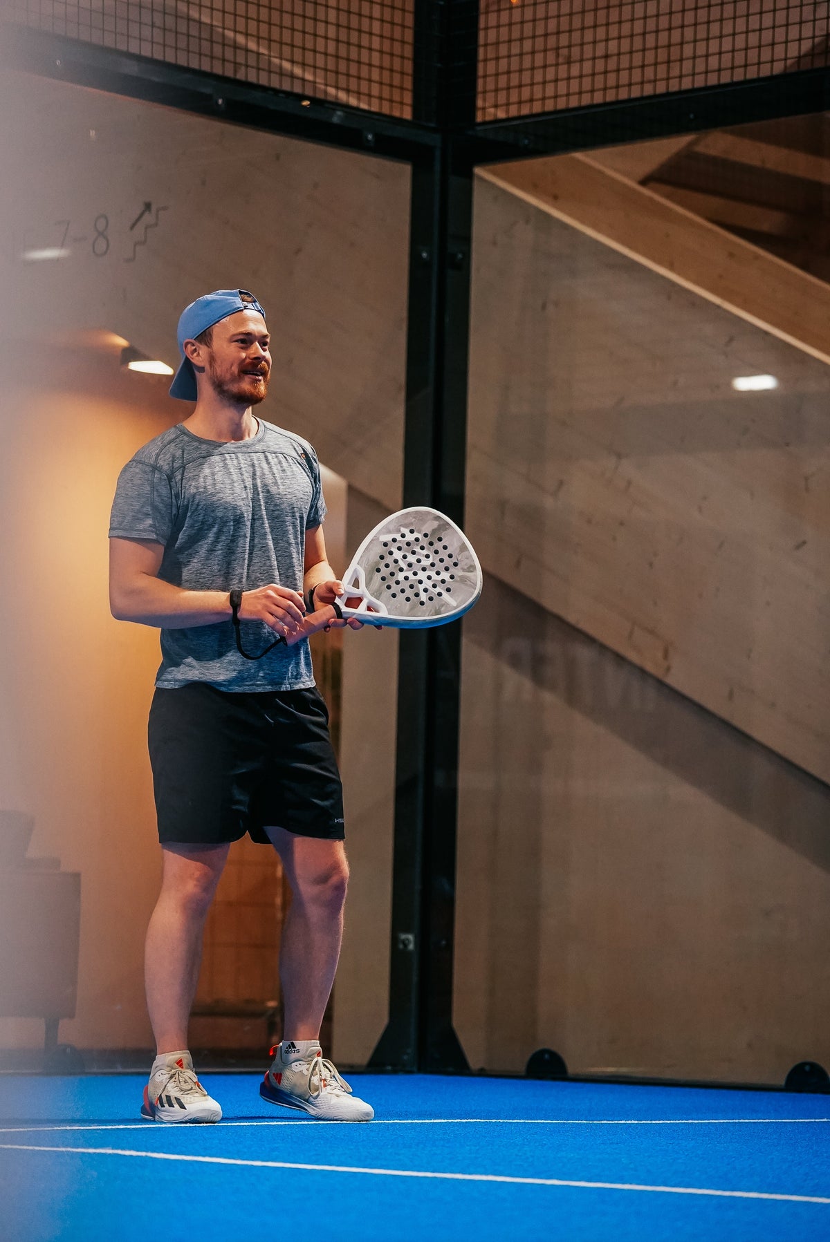 Two padel players at the net during a doubles rally on an indoor court