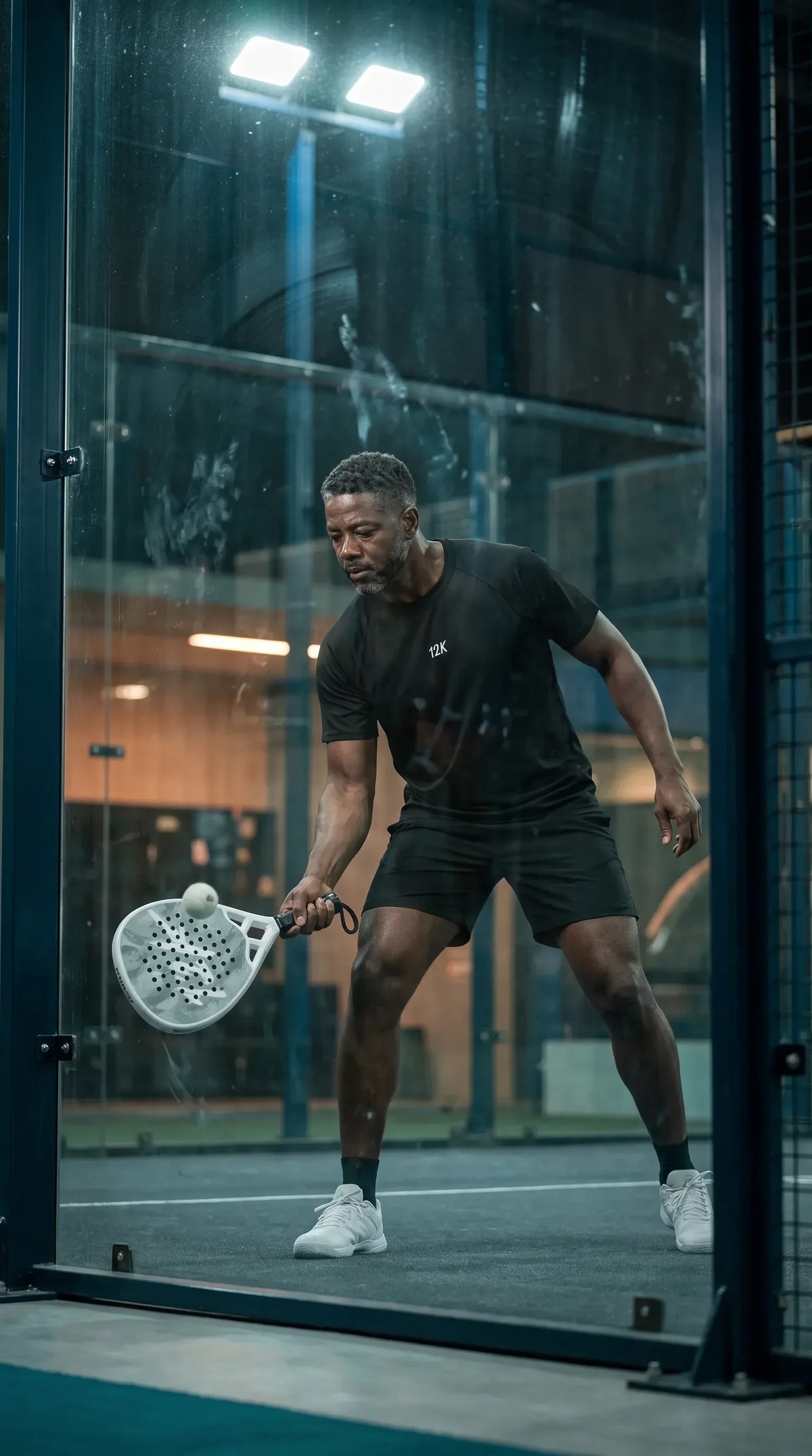 12K Padel Ice White racket, player set for a return behind the glass