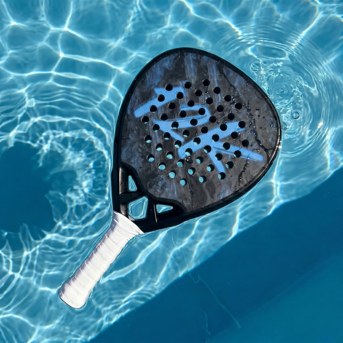 12K Padel Shark Blue racket floating in a swimming pool
